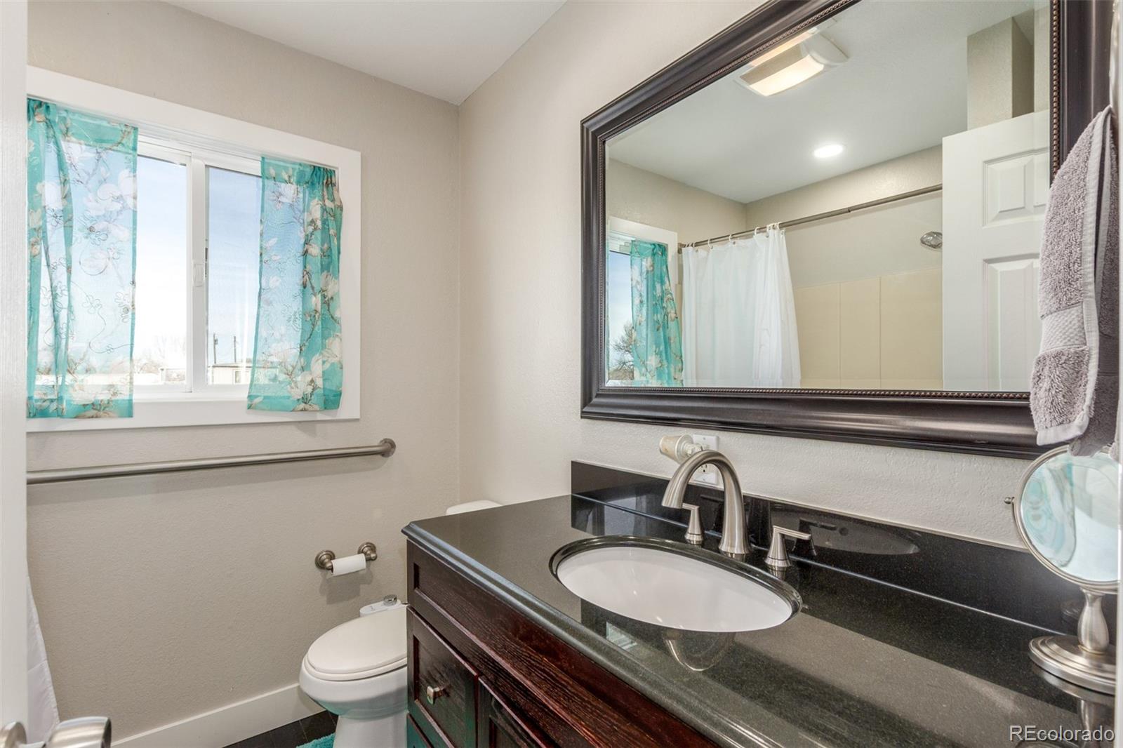 15528 Nancy Avenue Fort Lupton, CO 80621 - Photo 21 of 35 a bathroom with a granite countertop toilet a sink and a mirror