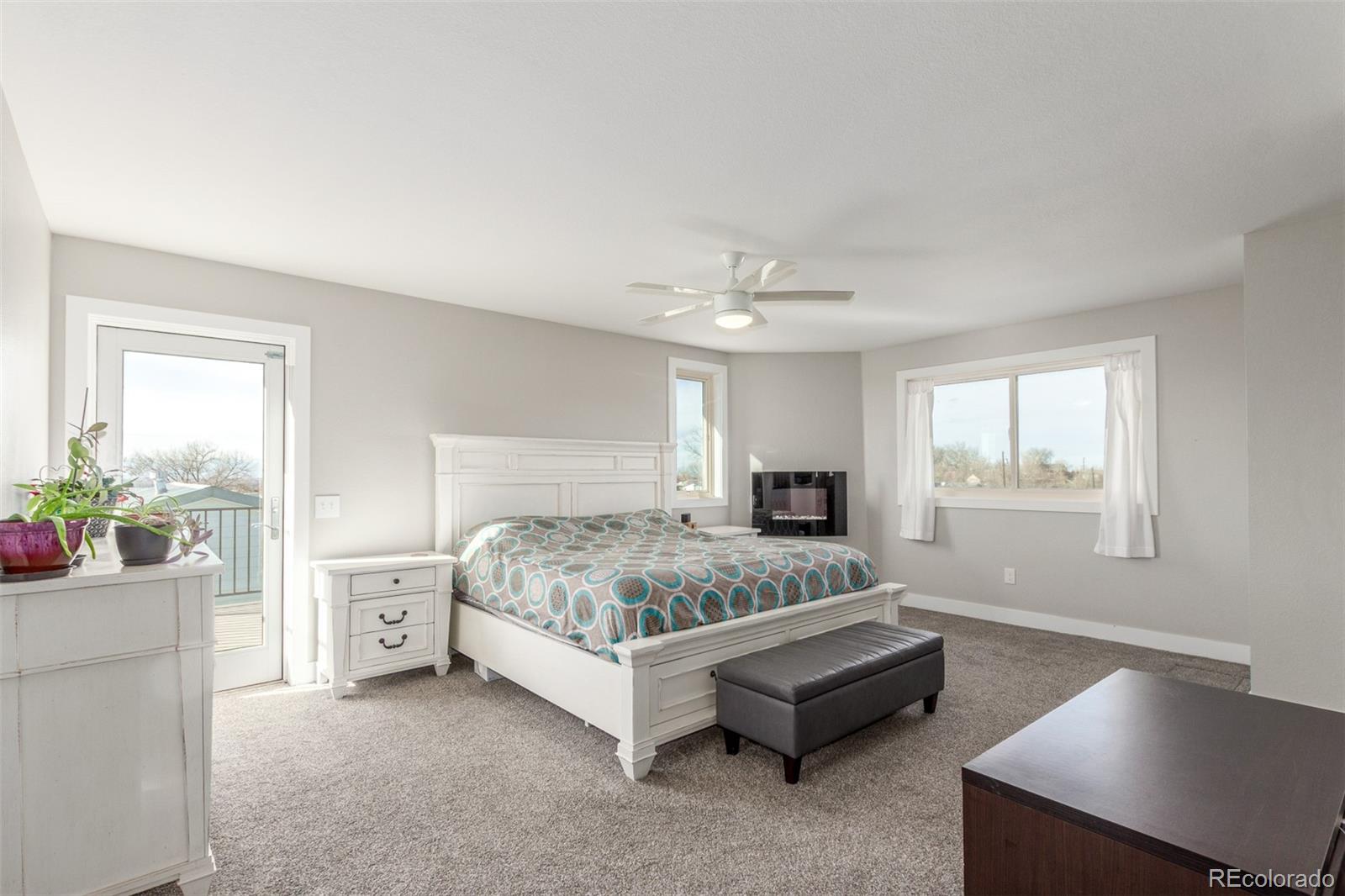 15528 Nancy Avenue Fort Lupton, CO 80621 - Photo 10 of 35 a spacious bedroom with a bed and a chandelier