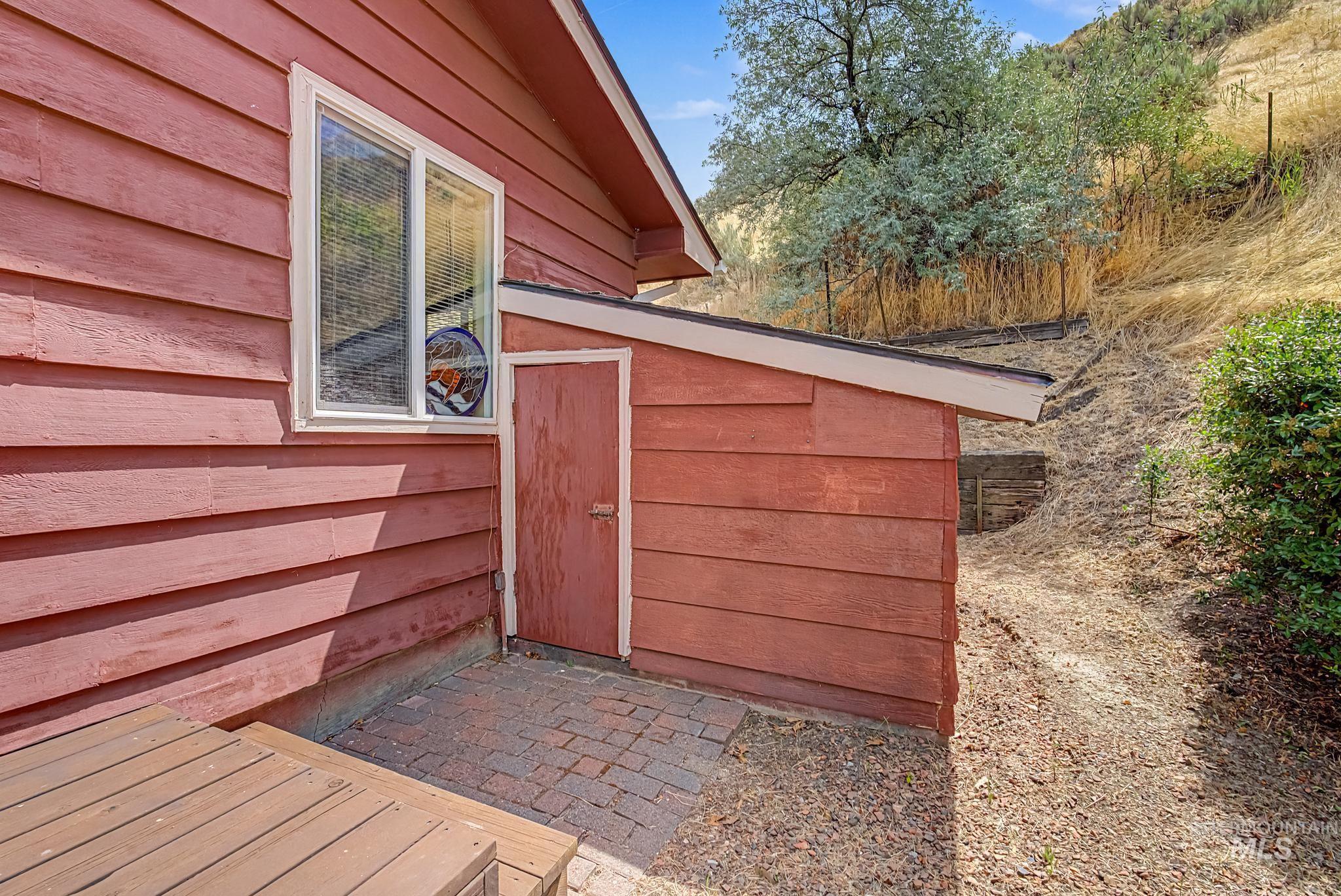 4311 Frozen Dog Road Emmett, ID 83617 - Photo 31 of 31 Exterior featuring red horizontal siding, a white-framed window, and a wood deck