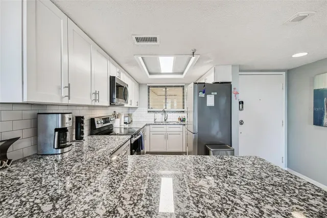 a bathroom with a granite countertop sink and a window