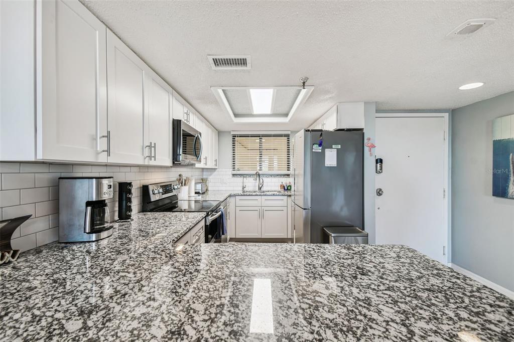5915 Sea Ranch Drive, Unit 108 Hudson, FL 34667 - Photo 8 of 92 a kitchen with stainless steel appliances kitchen island granite countertop a refrigerator and a stove top oven