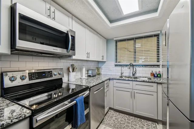 a kitchen with stainless steel appliances granite countertop a stove a sink and a microwave