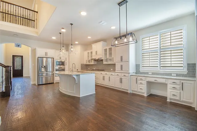 a large kitchen with granite countertop a large counter top a sink stainless steel appliances and cabinets