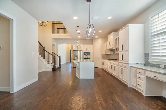 a open kitchen with white cabinets and wooden floor