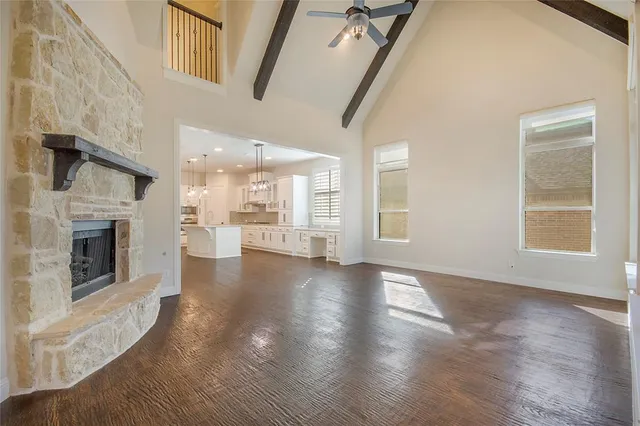 a view of an empty room with wooden floor and a fireplace