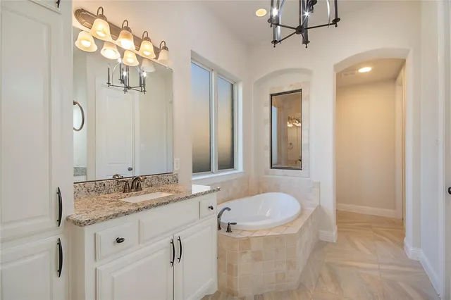 a bathroom with a granite countertop sink a mirror and a bathtub