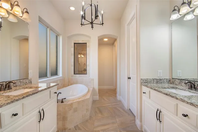 a bathroom with a granite countertop sink a mirror and a bathtub