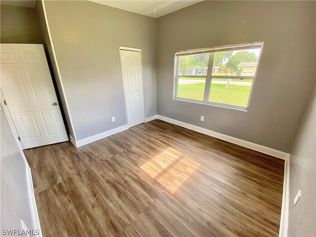402 Oregon Road West Lehigh Acres, FL 33936 - Photo 20 of 29 a view of an empty room with wooden floor and a window