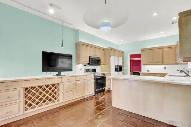 a kitchen with sink cabinets and flat screen tv