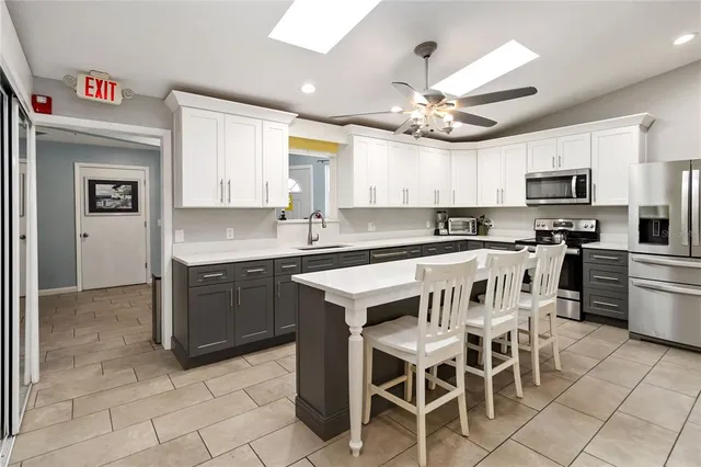 a kitchen with stainless steel appliances granite countertop a stove top oven a sink a dining table and chairs