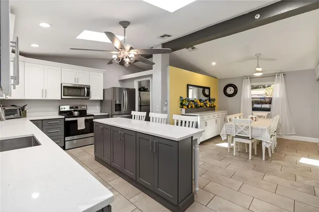 a kitchen with stainless steel appliances granite countertop a stove top oven a sink a dining table and chairs
