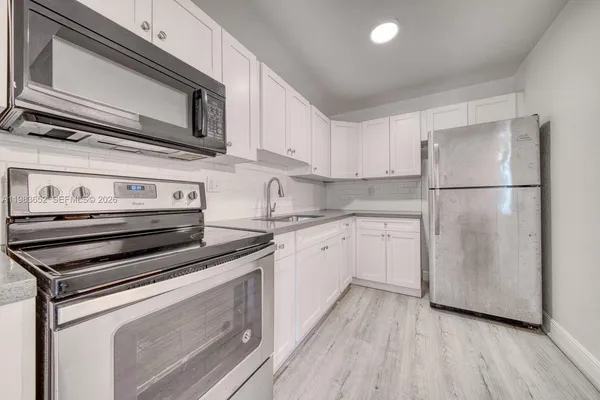 a kitchen with appliances a sink and lots of wooden cabinets