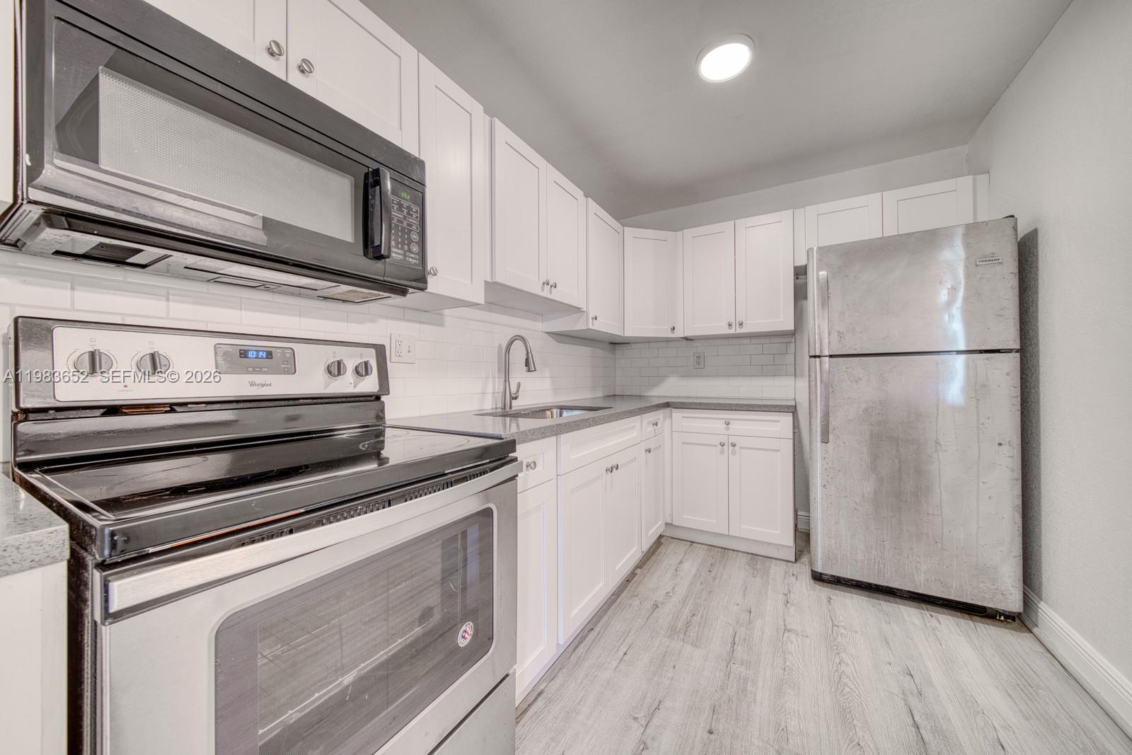 9459 Southwest 76th Street, Unit R5 Miami, FL 33173 - Photo 1 of 33 a kitchen with appliances a sink and lots of wooden cabinets