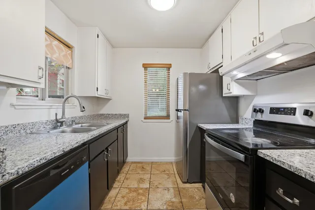 a kitchen with granite countertop stainless steel appliances a sink stove and cabinets