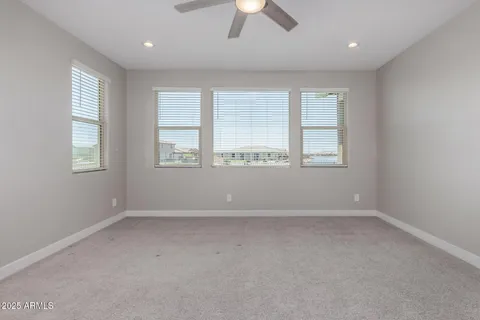 an empty room with chandelier fan and windows