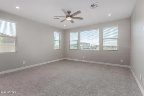 an empty room with windows and ceiling fan