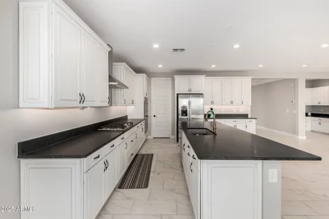 a large kitchen with stainless steel appliances granite countertop a sink a stove and a refrigerator