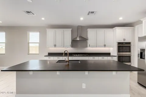 a large kitchen with granite countertop a stove a sink a counter space and cabinets