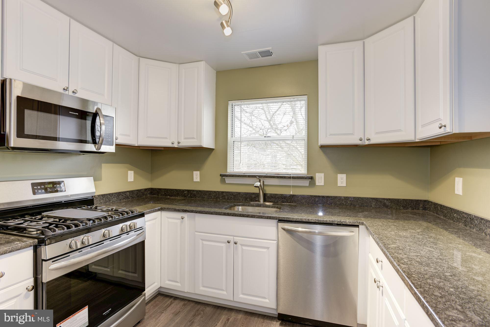 20579 Snowshoe Square, Unit 301 Ashburn, VA 20147 - Photo 11 of 30 a kitchen with granite countertop a sink stainless steel appliances and white cabinets