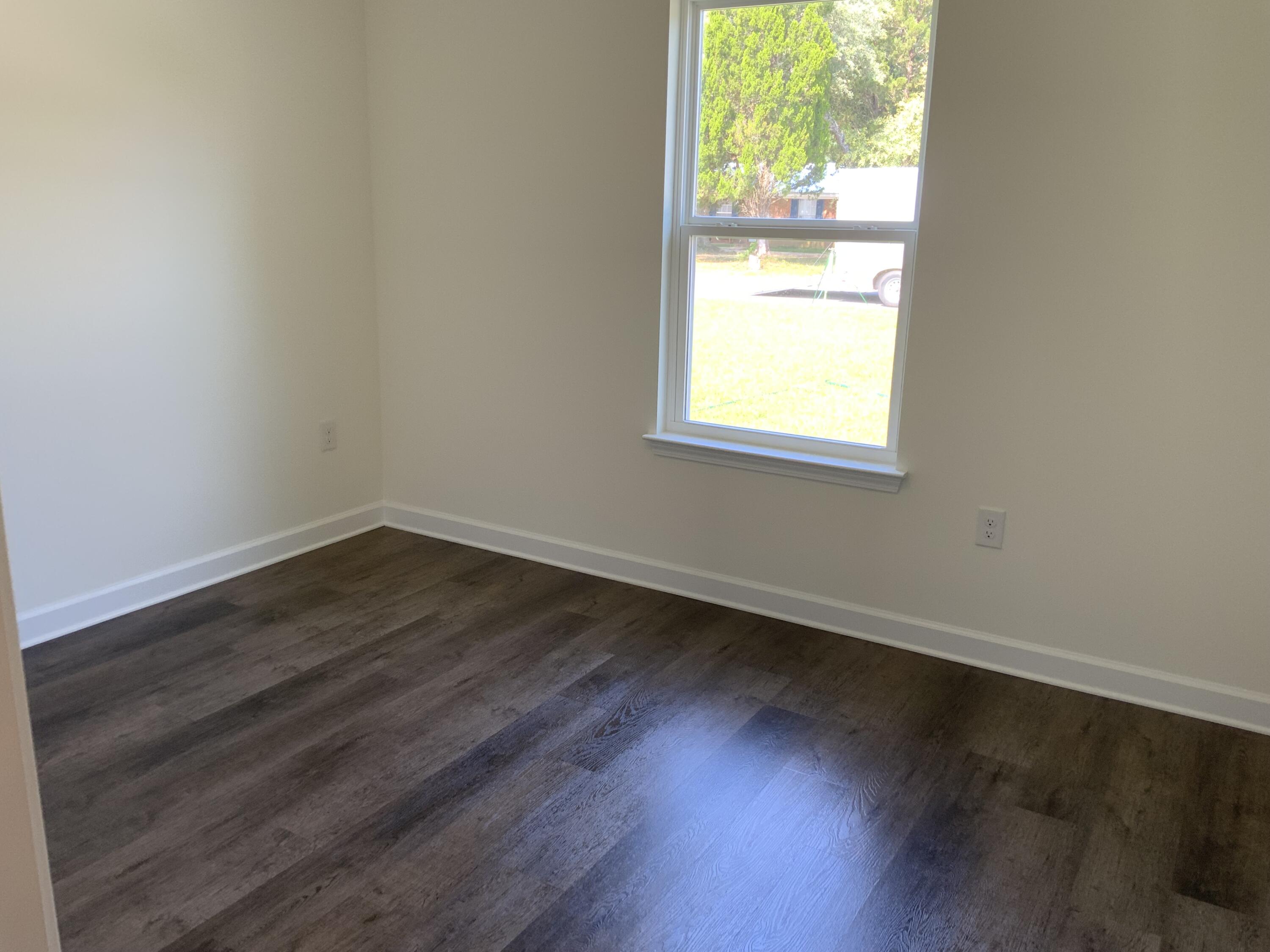 5835 Flamingo Road Crestview, FL 32539 - Photo 9 of 12 an empty room with wooden floor and windows