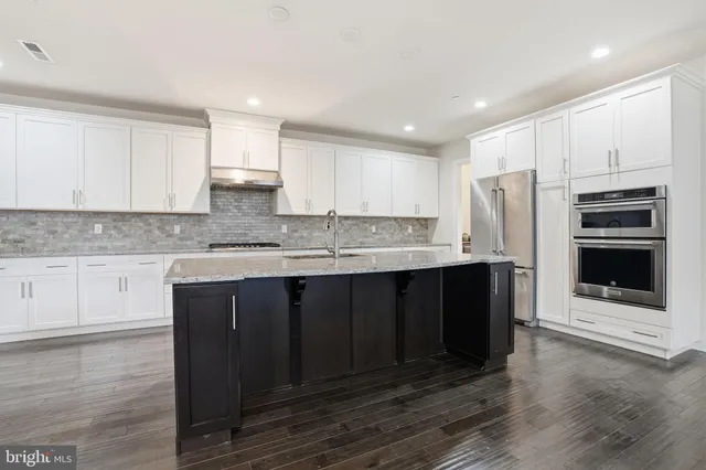a kitchen with stainless steel appliances granite countertop a stove a sink and a refrigerator