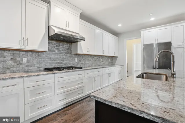 a kitchen with granite countertop white cabinets and a sink
