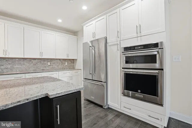 a kitchen with granite countertop a refrigerator stove and microwave