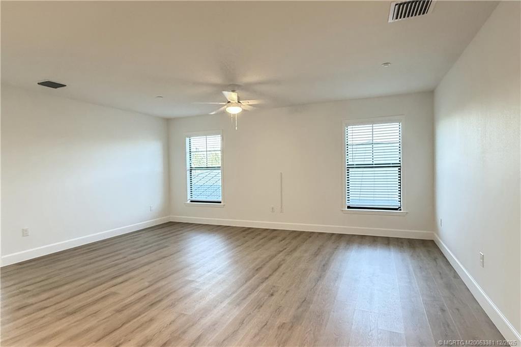3375 Southwest Mapp Road, Unit 203 Palm City, FL 34990 - Photo 13 of 22 an empty room with wooden floor chandelier fan and windows