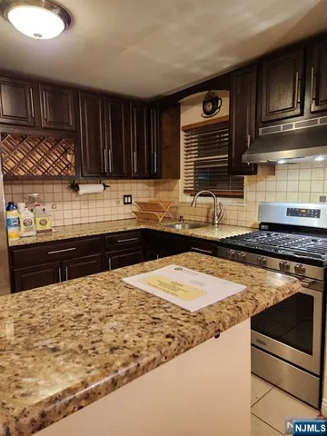 a kitchen with stainless steel appliances granite countertop a stove a sink and a microwave