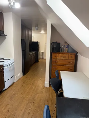 a view of kitchen and empty room with wooden floor