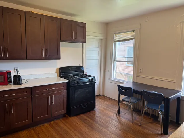 a kitchen with granite countertop wooden cabinets a stove a sink and a window