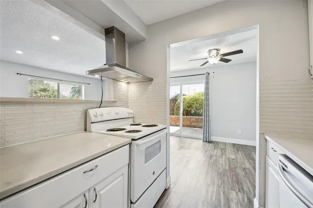 a kitchen with stainless steel appliances a stove a sink and white cabinets with wooden floor