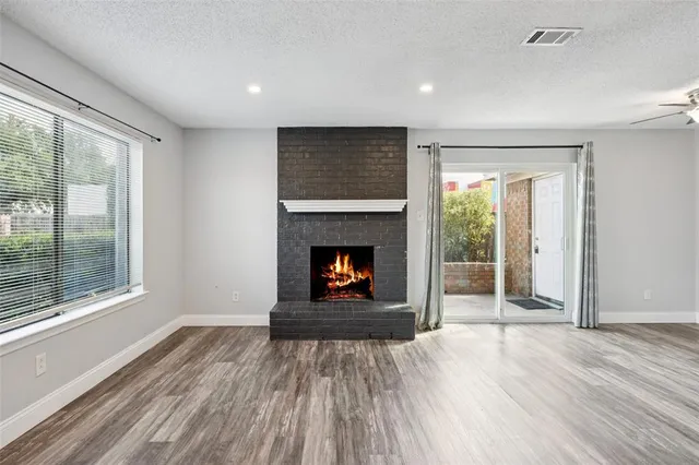 a view of an empty room with wooden floor fireplace and a window