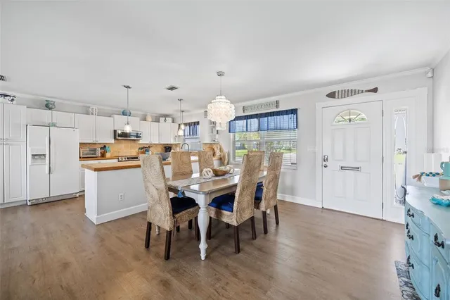 a kitchen with stainless steel appliances a dining table chairs and wooden floor