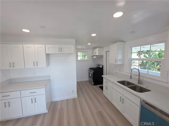 a kitchen with counter top space a sink stainless steel appliances and windows