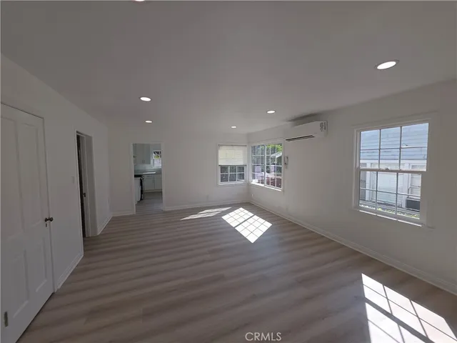a view of empty room with wooden floor and window