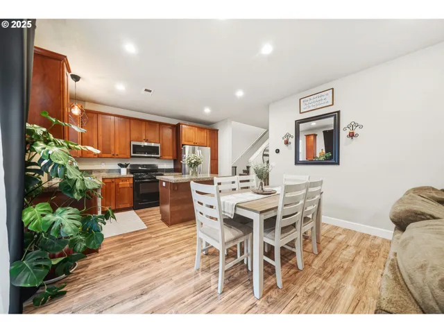 a open kitchen with stainless steel appliances kitchen island granite countertop a dining table chairs and granite counter tops