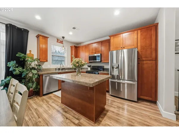 a kitchen with stainless steel appliances granite countertop a refrigerator a sink stove and a refrigerator