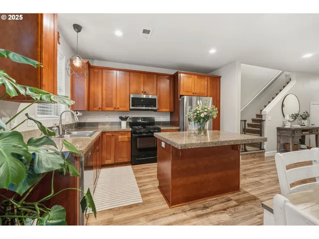 a kitchen with stainless steel appliances kitchen island granite countertop a stove a sink dishwasher and a microwave with wooden floor