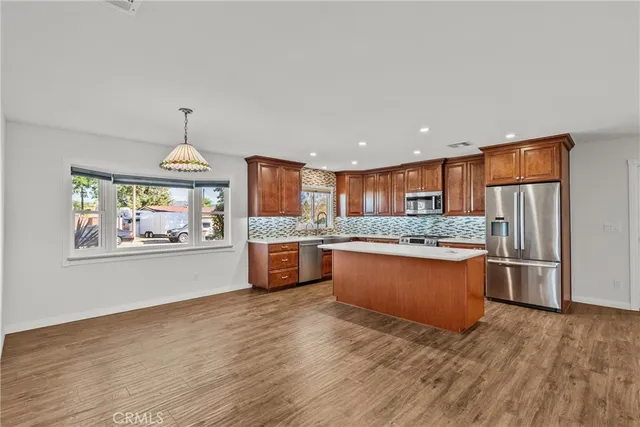 a large kitchen with granite countertop a large counter top stainless steel appliances and wooden floor