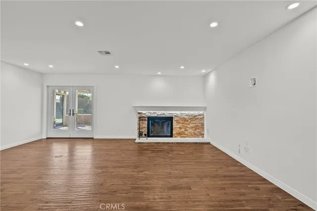 a view of an empty room with wooden floor and a fireplace