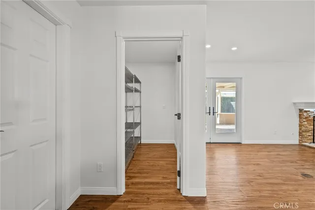 a view of an empty room with wooden floor and a bathroom