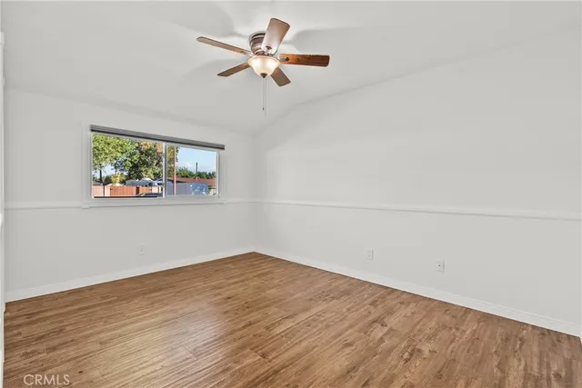 an empty room with wooden floor a ceiling fan and window