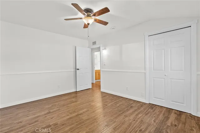 an empty room with wooden floor fan and windows