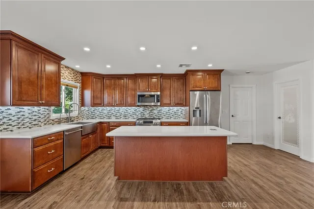 a large kitchen with wooden floors and stainless steel appliances