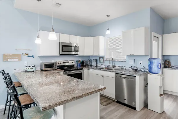 a kitchen with stainless steel appliances granite countertop a stove top oven a sink a microwave and refrigerator