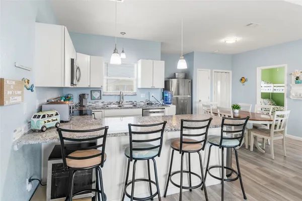 a kitchen with stainless steel appliances kitchen island granite countertop a dining table chairs and sink