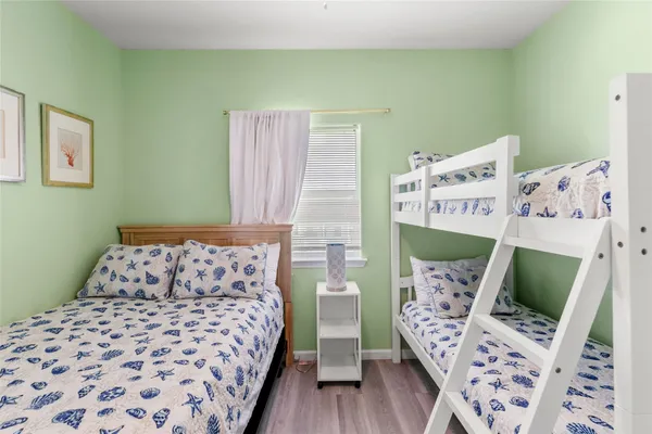 a bedroom with a bed next to a window with wooden floor