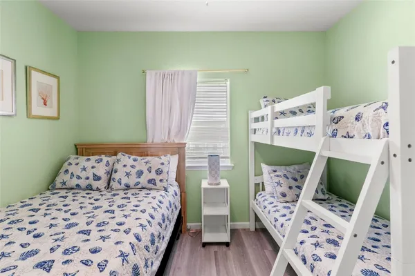 a bedroom with a bed next to a window with wooden floor