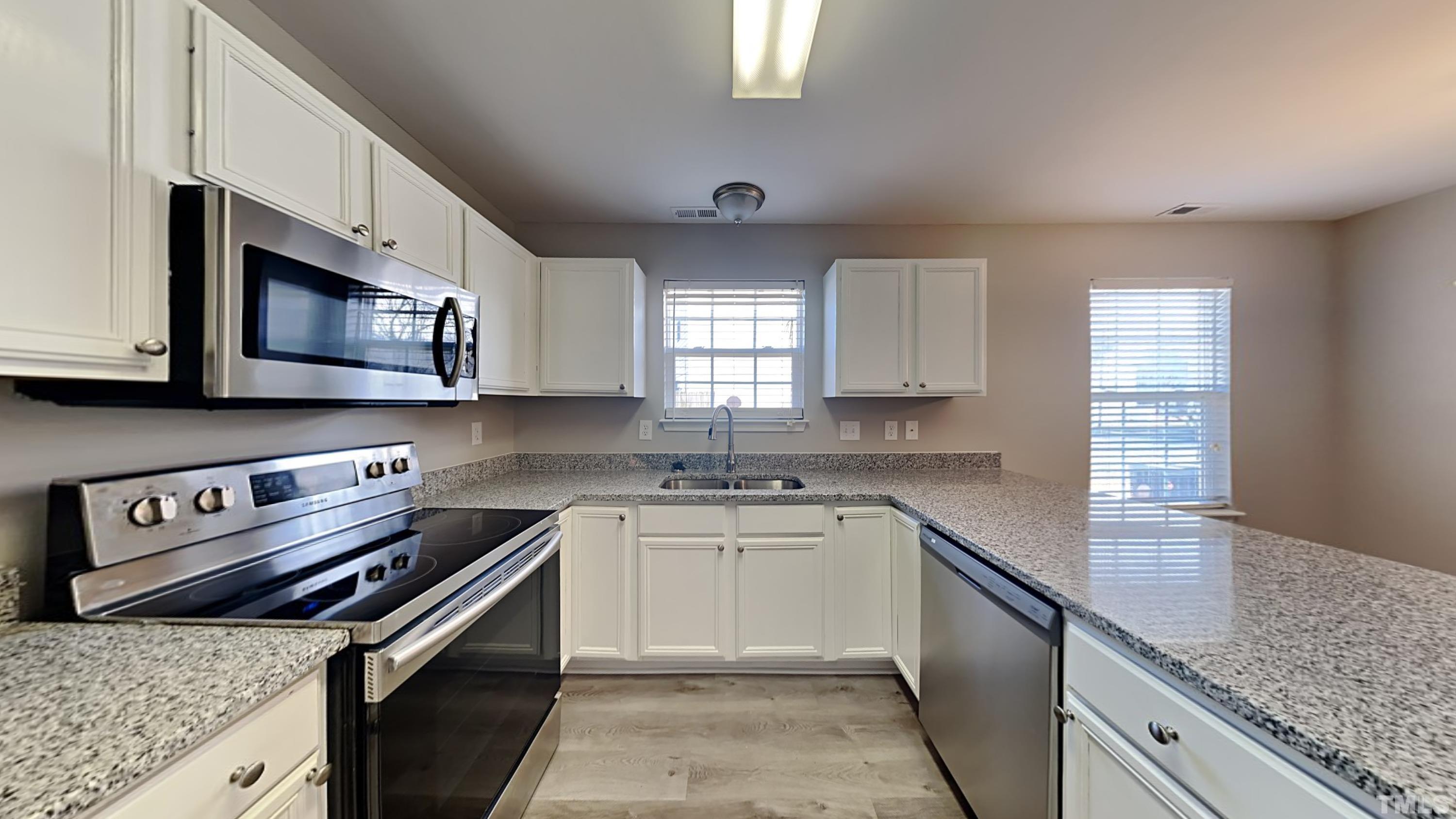 4105 Springfield Creek Drive Raleigh, NC 27616 - Photo 4 of 12 a kitchen with stainless steel appliances granite countertop a sink stove microwave and cabinets